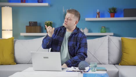 home office worker man scratches his ears looking at camera.