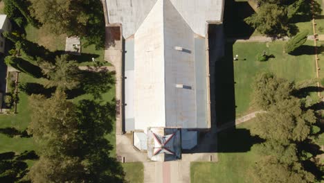 aerial top down dolly in of an idyllic romantic style church surrounded by trees, santa anita, entre rios, argentina