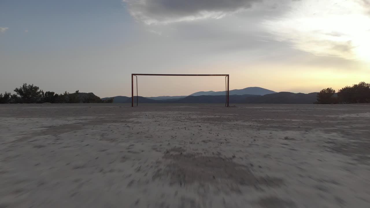 antena: drone volando hacia la portería de fútbol vacía cerca de suelo duro
