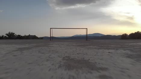 aerial: drone flying towards empty football goal close over hard ground