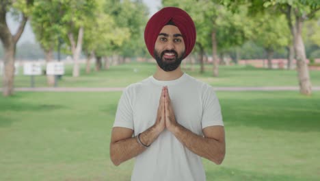 happy sikh indian man greeting and doing namaste in park