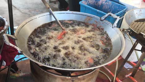 handheld-medium-shot-of-deep-fry-pan-on-a-local-street-food-stall-in-Rawai,-Phuket,-Thailand