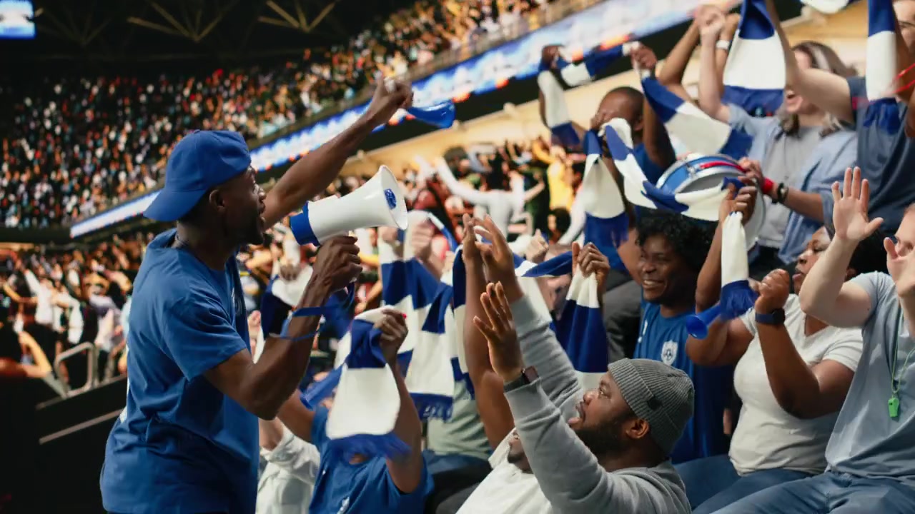 Líder de fútbol del equipo azul de pie sobre la multitud con un megáfono.