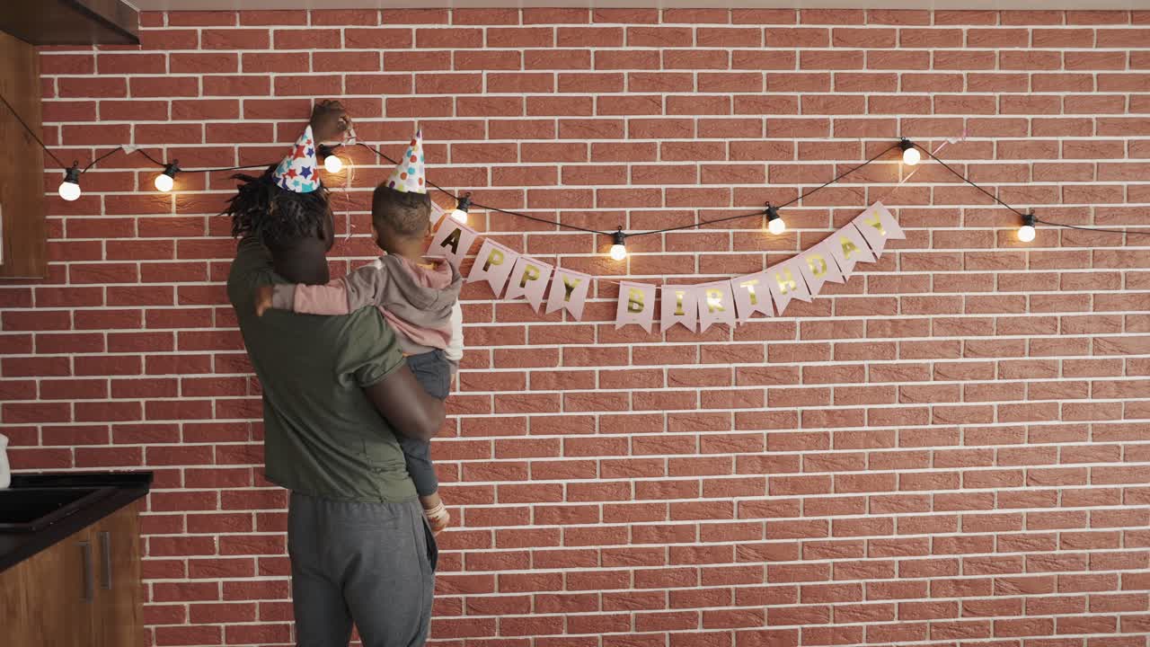 African American decorating baby boy's birthday party in the living room