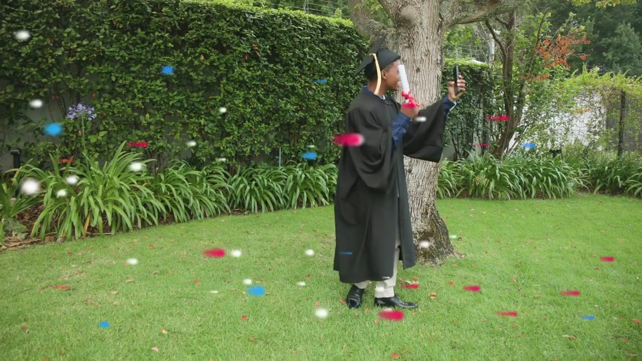 Laureato che alza il telefono e mostra il diploma in giardino mentre i coriandoli che cadono lo superano segnalano la laurea