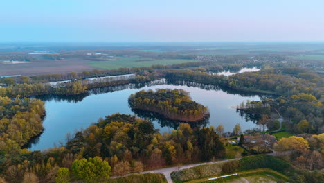 Serene Dutch landscape aerial. Vibrant greenery surrounds a tranquil body of water in the Netherlands, showcasing natural beauty during sunset