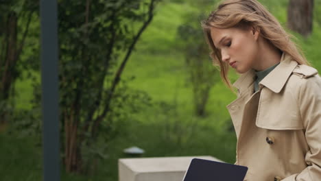 caucasian female student writing in notebook at the park.