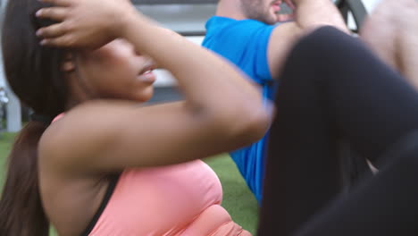 two people doing cycling side crunches in a gym