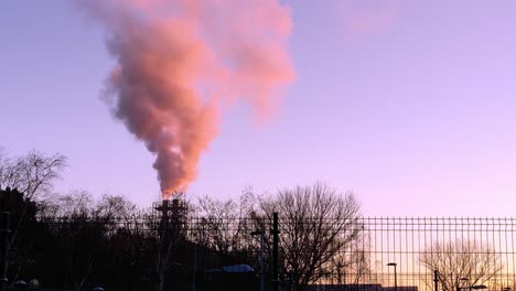 emisiones contaminantes liberadas de una fábrica ubicada en el área urbana durante la puesta de sol