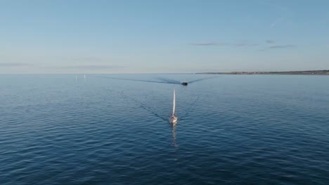 drone clip showing white sailboat and small fishing boat on calm sea