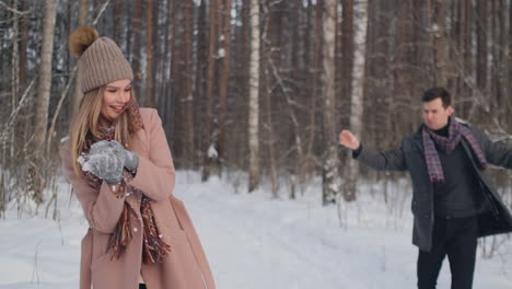 cámara lenta - pareja peleando con bolas de nieve en un campo. terminan su pelea en buenos términos con un choque de cinco.