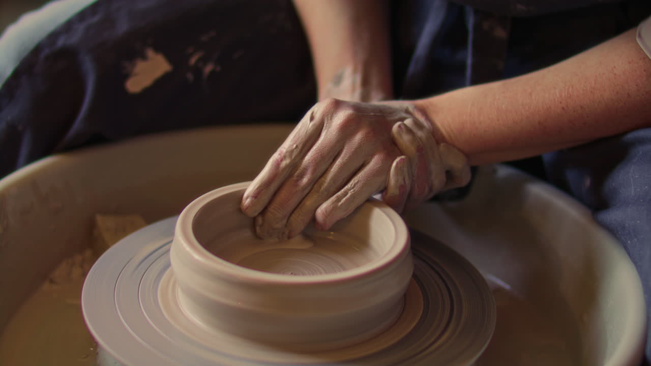 Hands of Ceramic Artist Shaping Cylindrical Clay Form on Pottery Wheel