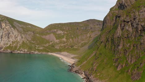 Aerial-shot-of-remote-Lofoten-Sandvika-beach-in-Noway-surrounded-by-steep-cliffs