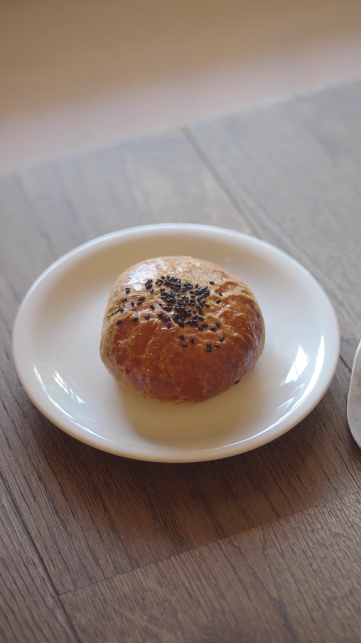 Sweet Baked Bun with Black Sesame Seeds on Wooden Table