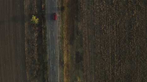 road trip through country roads. wide aerial view of a car driving along a secluded rural road.