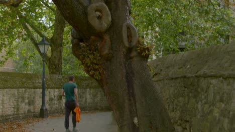 tracking shot of man walking down scenic alleyway in oxford