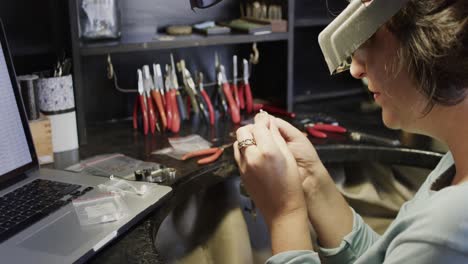 trabajadora caucásica inspeccionando un anillo con lupa en un taller en cámara lenta