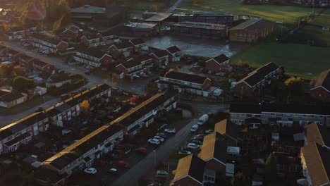 UK-Townhouse-estate-aerial-view-with-early-morning-sunrise-light-leaks-over-Autumn-coloured-trees-and-rooftops