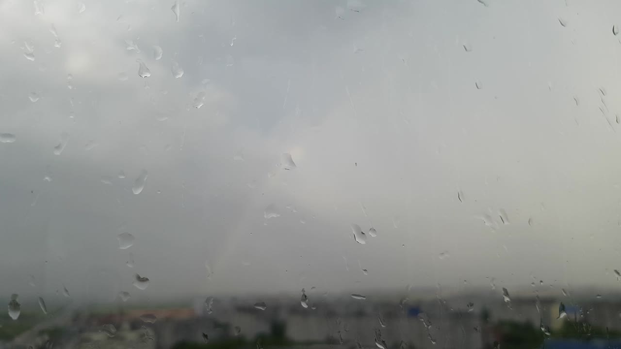 창문에 물방울이 떨어지고, 비가 내리고, 바에 무지개가 있습니다.