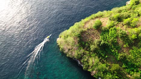 Barco-Navegando-En-La-Superficie-Del-Océano-Alrededor-De-La-Isla-En-Nusa-Penida,-Bali,-Indonesia