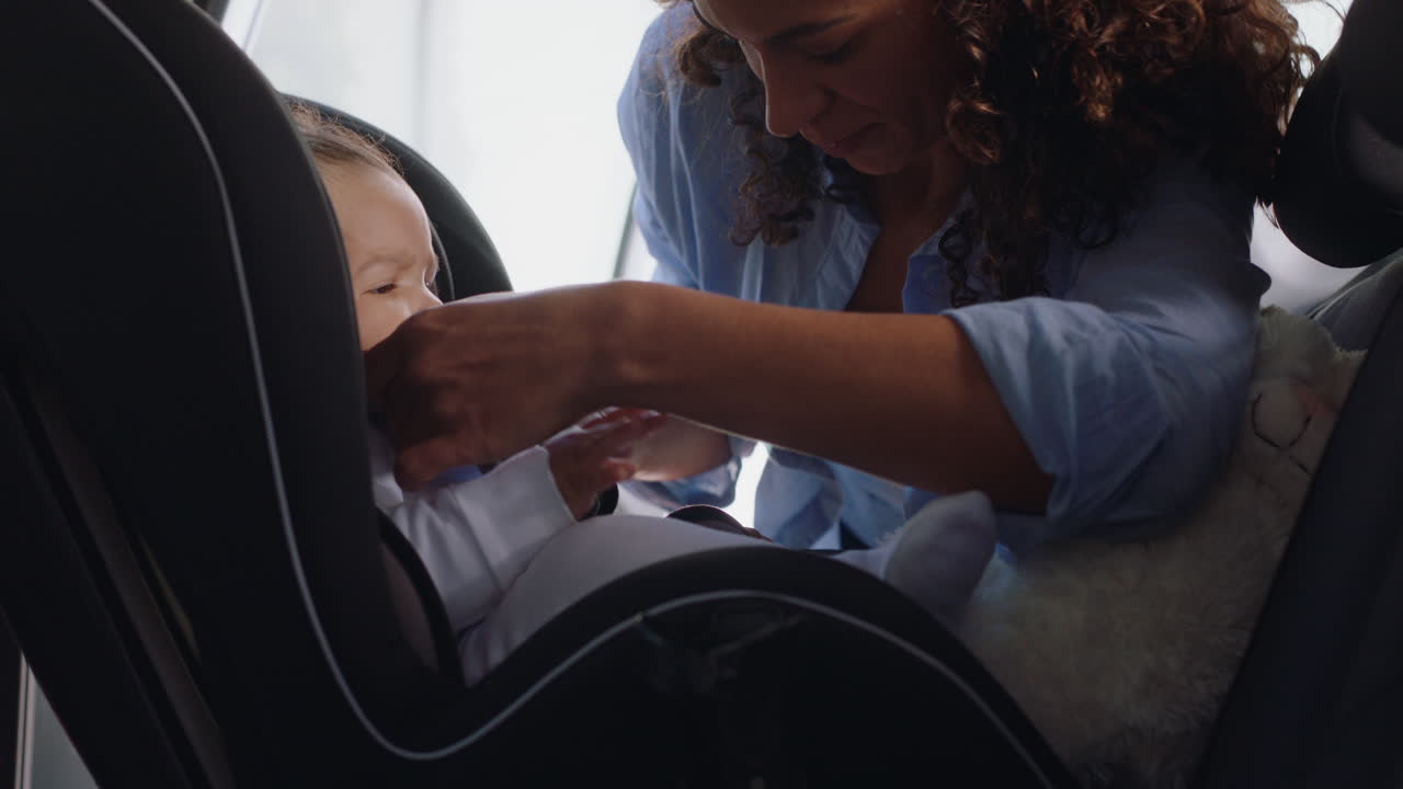 Young mother putting baby in car seat securing child for road trip ...