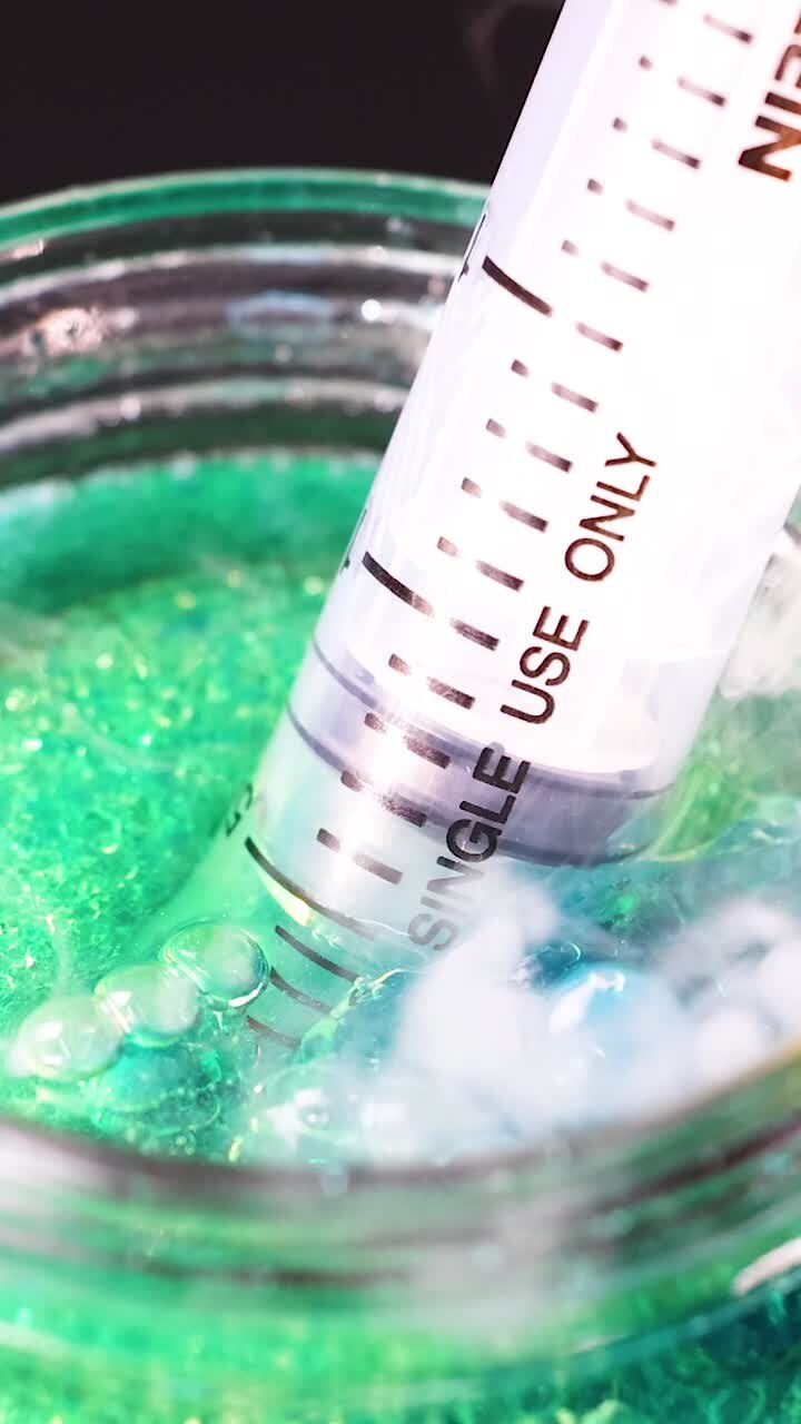 Siringa interagisce con liquido colorato in un barattolo