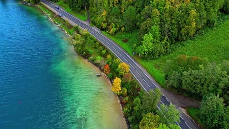 Vista-Aérea-De-Un-Coche-Negro-Que-Viaja-Por-Una-Carretera-Asfaltada-Alrededor-Del-Pintoresco-Lago-Attersee-En-El-Estado-Austriaco-De-Alta-Austria,-Salzkammergut,-Europa