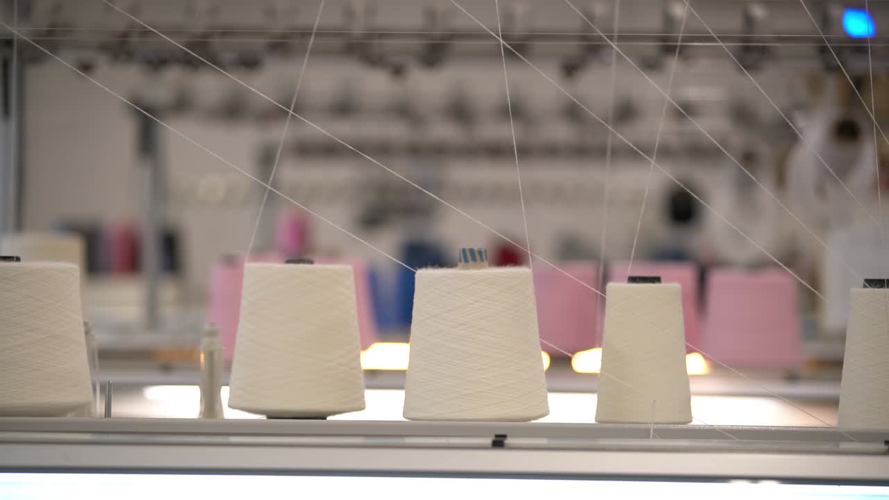 Spools of white thread on knitting device view