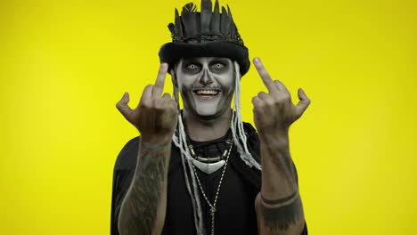 sinister man with skull makeup making faces and showing middle finger. bad manner gesture. halloween