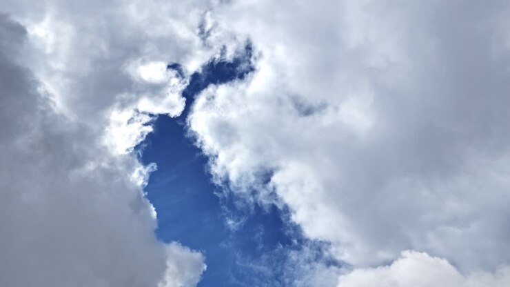 Skyformation af bløde hvide skyer med blå himmel, der bryder igennem på en solskinsdag