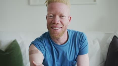 happy albino african american man with dreadlocks and a plaster after vaccination