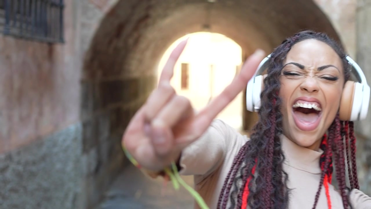 Una donna gioiosa e allegra che si gode la musica mentre è seduta in un vivace vicolo urbano.