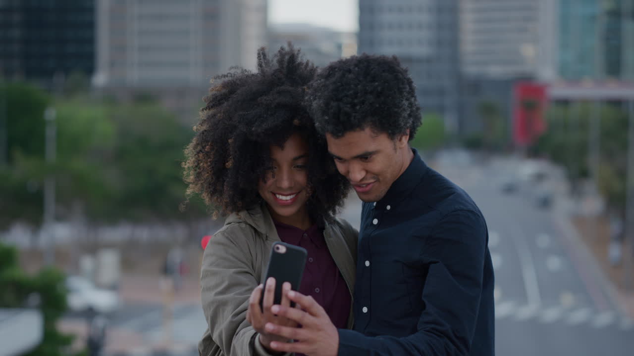 portrait young african american couple using smartphone taking photos making faces enjoying relaxed urban lifestyle together in city happy relationship technology connection