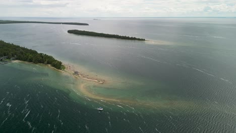sand spit on island tip with boats in water, hessel, michigan
