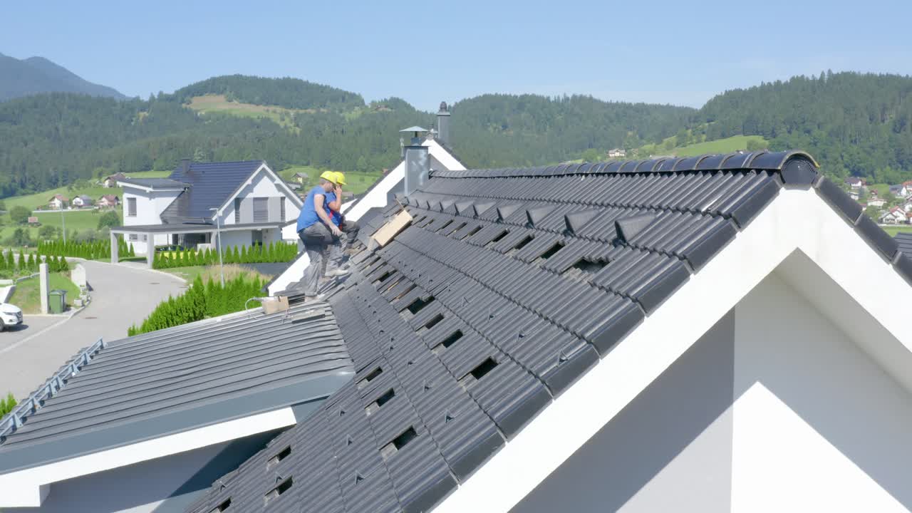 Roofer with yellow helmet talking on the phone. Sideways shot
