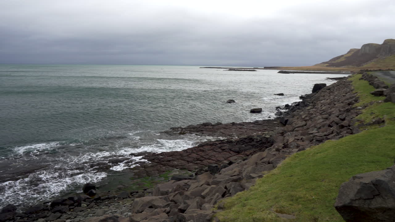 Panning shot of waves splashing on the rocks on a cloudy day in Scotland, isle of Skye