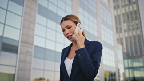 una mujer irritada quejándose de su teléfono inteligente caminando por el distrito comercial de la ciudad de cerca.