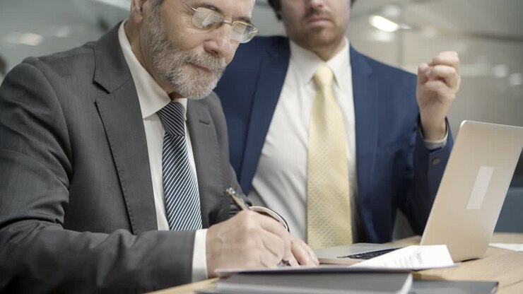 Grey-haired customer in glasses signing contract