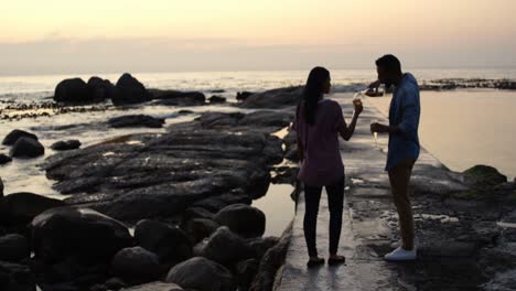 mixed-race couple having wine at beach during sunset 4k