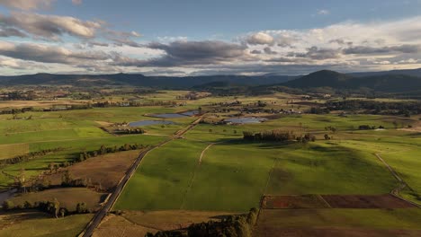 4k60 drone view over rural landscape in australia with green fields, mountains and epic clouds