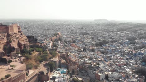 jodhpur blue cityscape contrasting with mehrangarh fort in rajasthan, india - aerial panoramic reveal shot