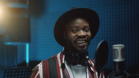 young good looking cheerful man singer taking off headphones and smiling to the camera after recording a song in the sound studio