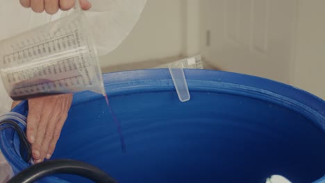 person in protective gear working with a blue barrel