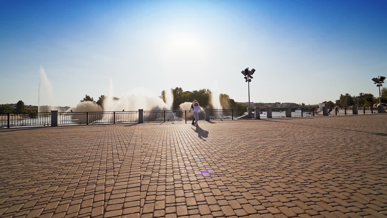 Couple dancing near water. Cheerful young couple dancing against fountain