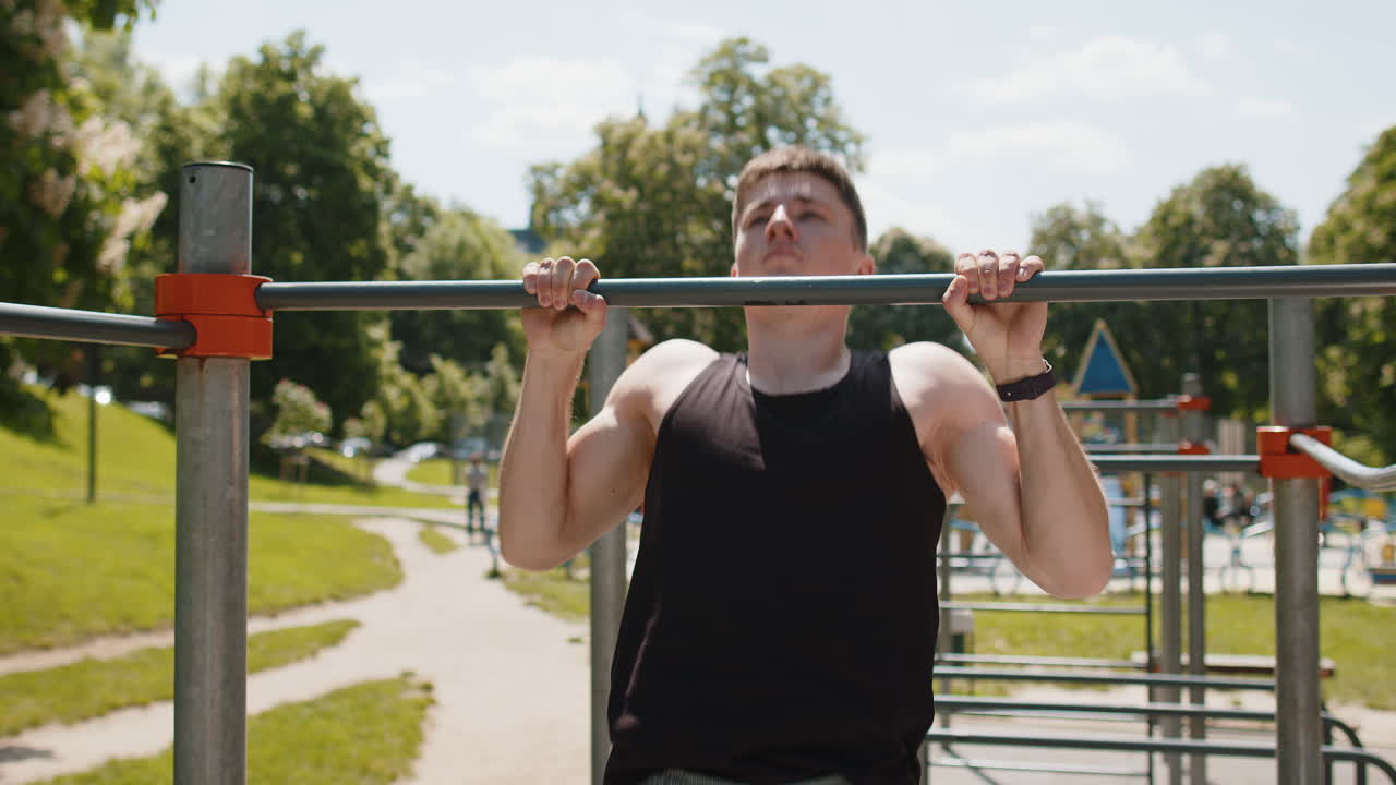 Athletic caucasian man in sportswear doing pull ups exercises on horizontal bar pumping up back
