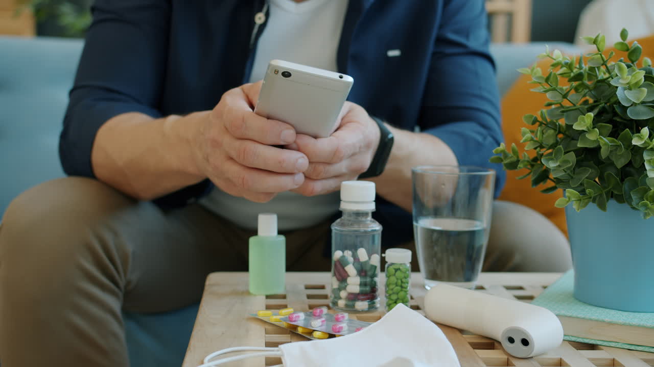 Man using phone with medication and health supplies