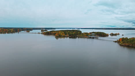 Eine-Lange-Hängebrücke-über-Einen-See-Entlang-Von-Inseln,-Umgeben-Von-Einem-Herbstwald-Mit-Grünen,-Roten,-Gelben-Und-Braunen-Bäumen-In-Valkeakoski,-Finnland