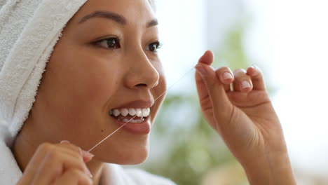 mujer lavándose los dientes con hilo dental