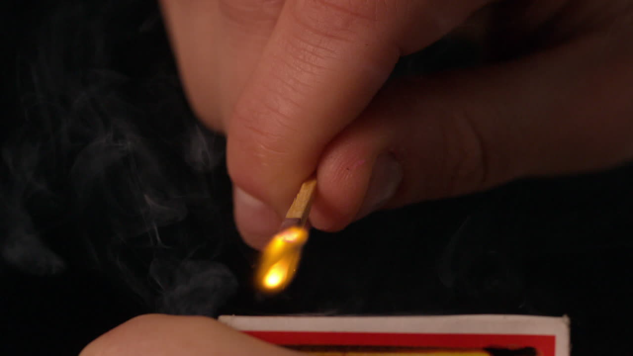 la mano encendiendo un fósforo sobre un fondo negro