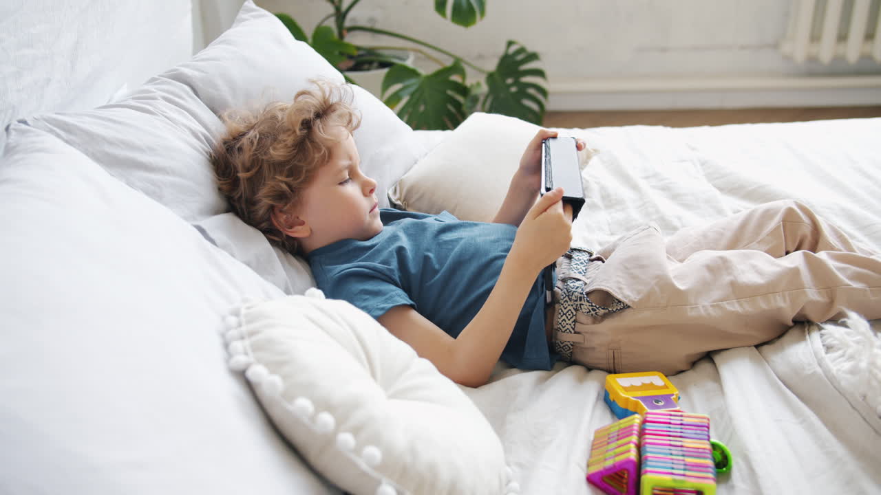 Child Playing on Tablet in Bed